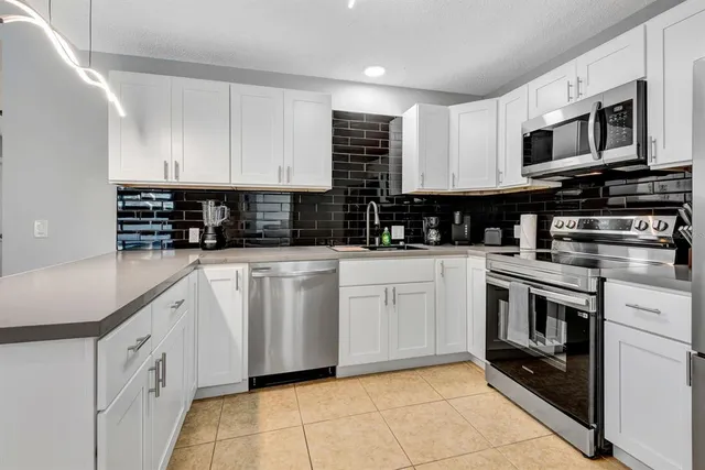 a kitchen with white cabinets stainless steel appliances and a sink