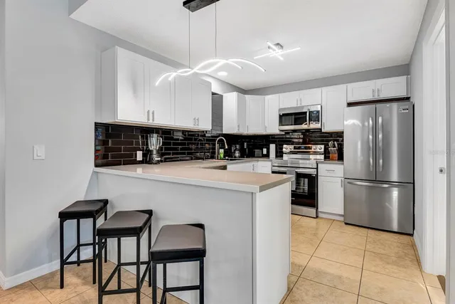 a kitchen with stainless steel appliances granite countertop a sink a stove a refrigerator and island