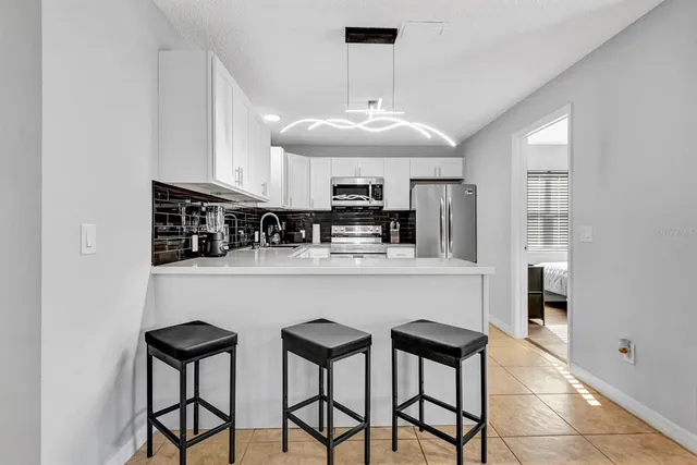 a kitchen with stainless steel appliances granite countertop a table chairs sink and cabinets