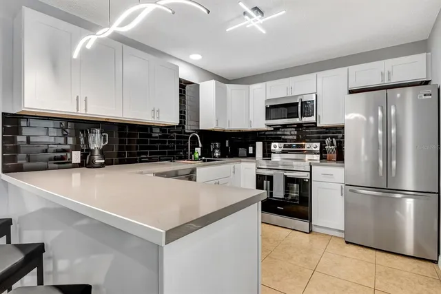 a kitchen with granite countertop a refrigerator and a stove top oven