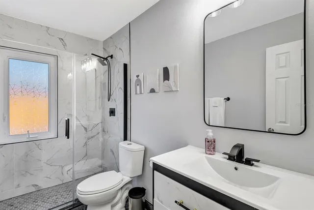 a bathroom with a sink a toilet and shower a mirror