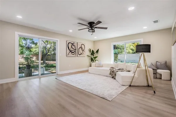 a living room with furniture large window and wooden floor