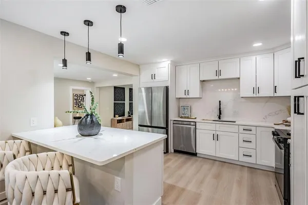 a kitchen with stainless steel appliances kitchen island granite countertop a dining table chairs and white cabinets