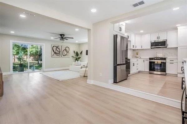 an empty room with wooden floor and a kitchen