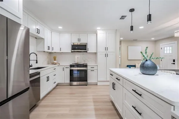 a kitchen with stainless steel appliances kitchen island granite countertop a stove a sink a refrigerator and a refrigerator