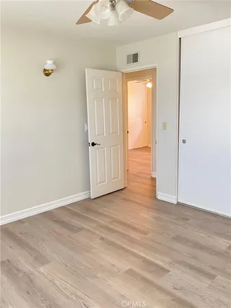 a view of empty room with wooden floor and fan