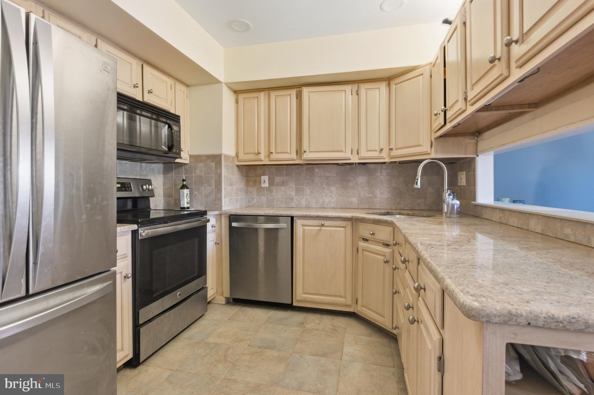 a kitchen with granite countertop a sink stainless steel appliances and cabinets