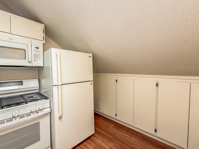 a white refrigerator freezer and a stove sitting inside of a kitchen