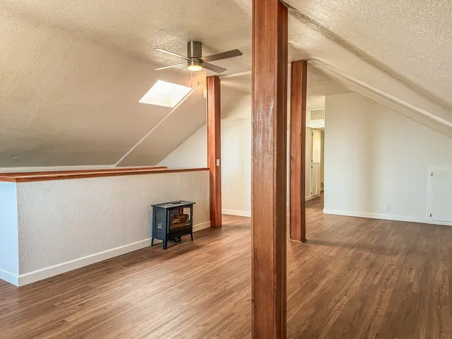 an empty room with wooden floor a ceiling fan and windows
