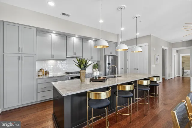 a kitchen with stainless steel appliances granite countertop a sink a stove and a wooden floors