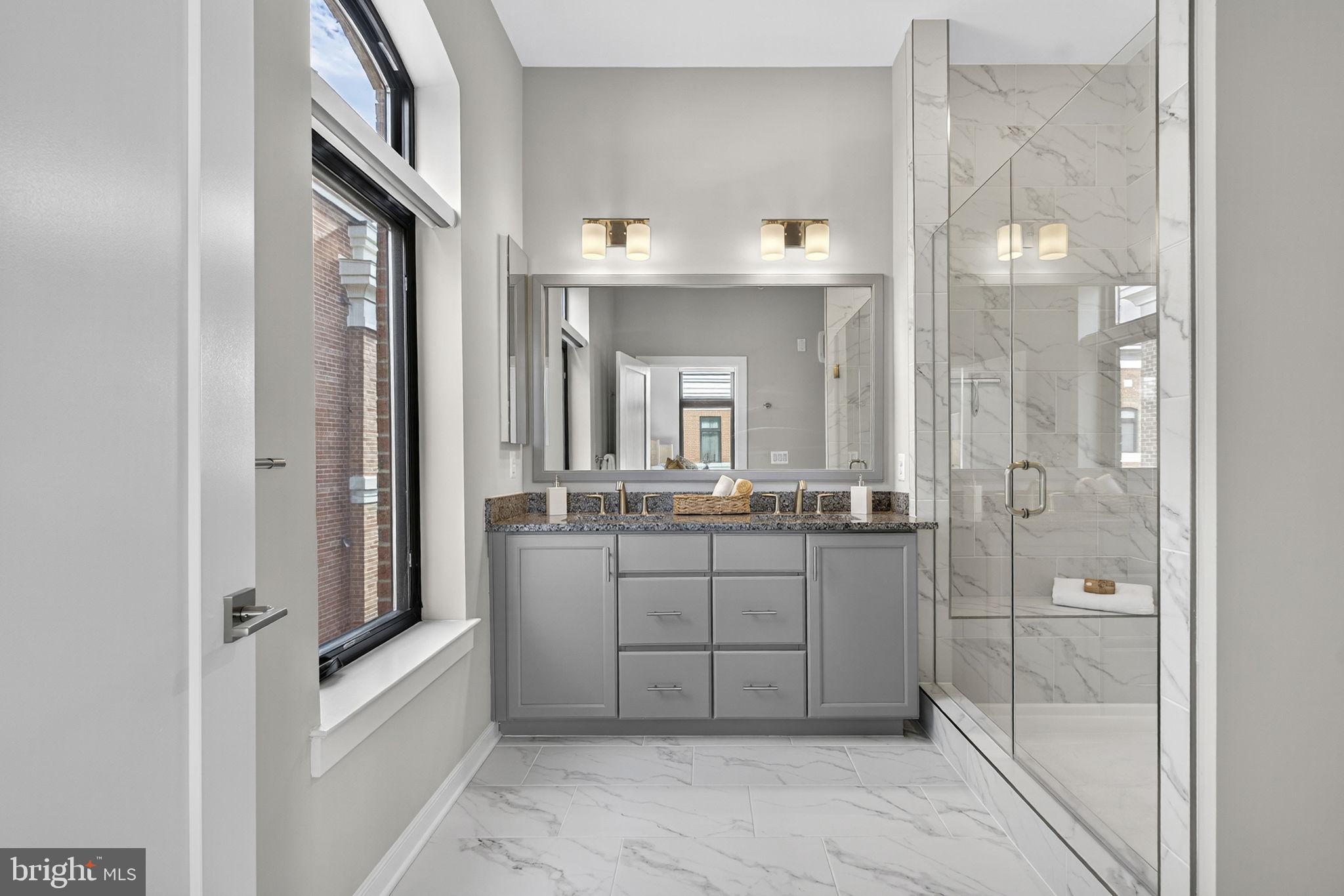 3 Stationmaster Street Southeast, Unit 402 Leesburg, VA 20175 - Photo 14 of 46 a bathroom with a double vanity sink a mirror a bathtub and shower