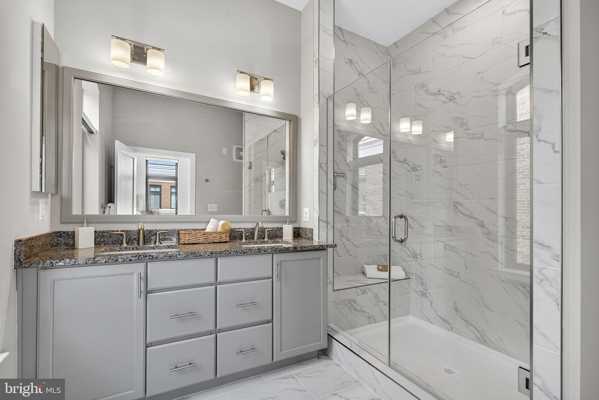 3 Stationmaster Street Southeast, Unit 402 Leesburg, VA 20175 - Photo 16 of 46 a bathroom with a granite countertop sink mirror and a shower
