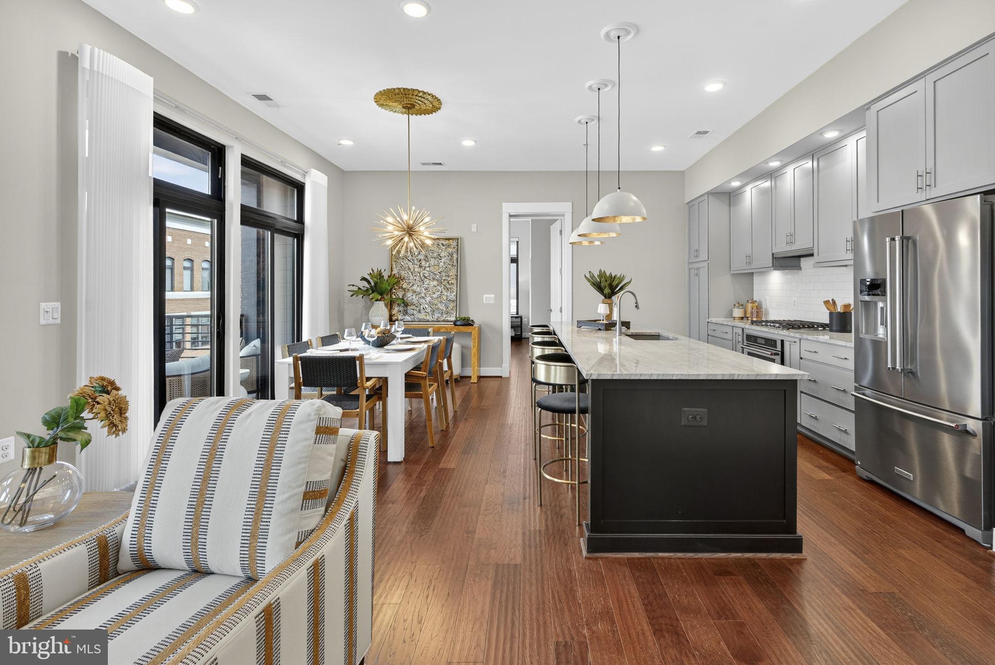 3 Stationmaster Street Southeast, Unit 402 Leesburg, VA 20175 - Photo 6 of 46 a kitchen with stainless steel appliances granite countertop a refrigerator a stove top oven a dining table and chairs with wooden floor
