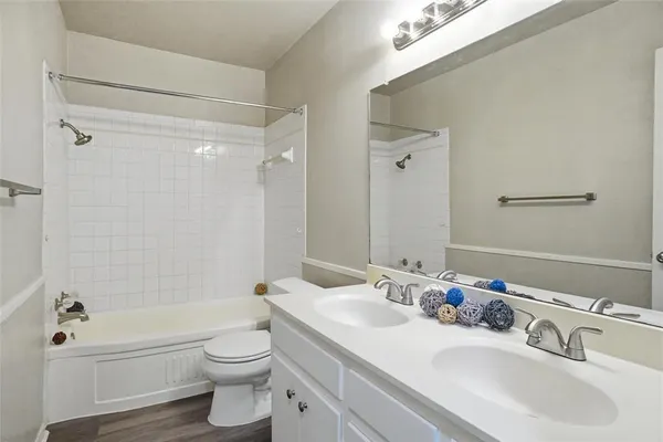 a bathroom with a bathtub shower sink vanity mirror and toilet