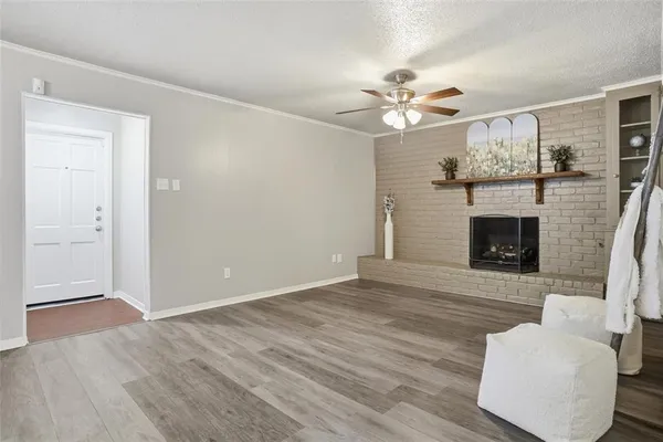 an empty room with wooden floor a ceiling fan a fireplace and windows