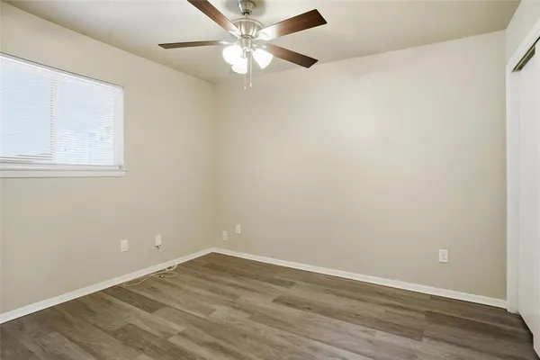 an empty room with wooden floor and fan