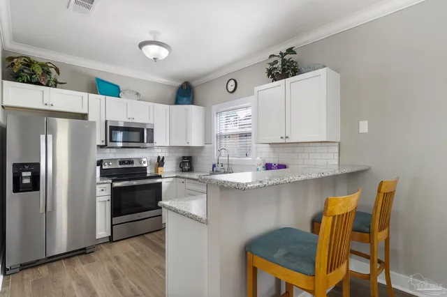 a kitchen with stainless steel appliances kitchen island granite countertop a table chairs microwave and sink