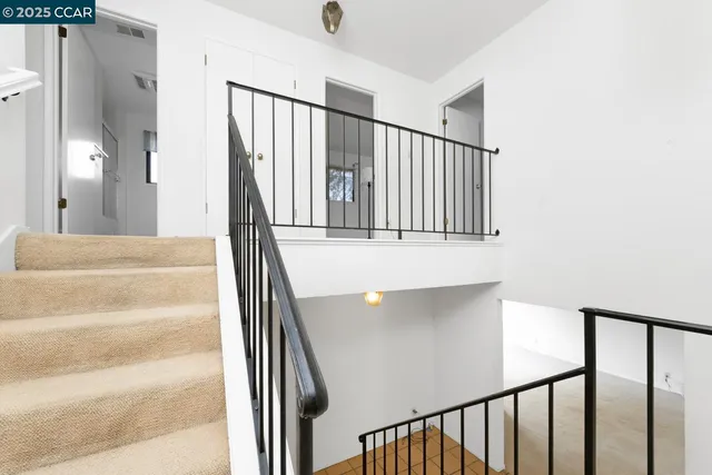 a view of staircase with railing and white walls