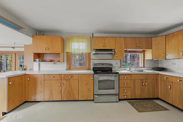 a kitchen with stove a sink and white cabinets