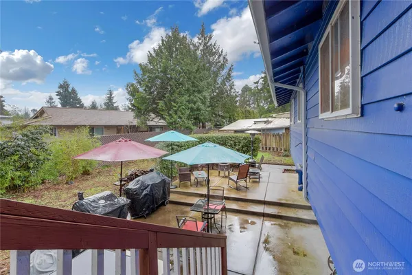 a view of patio with chairs and table under an umbrella with wooden fence