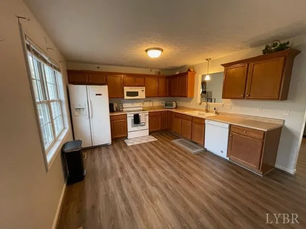 a kitchen with stainless steel appliances granite countertop a refrigerator a sink dishwasher a stove and white countertops with wooden floor