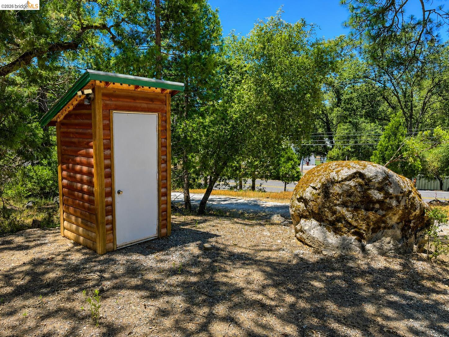 21181 Phoenix Lake Road Sonora, CA 95370 - Photo 6 of 34 Freestanding wooden structure with a green sloped roof and white door, situated on a gravel surface