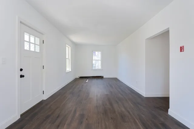 an empty room with wooden floor and window