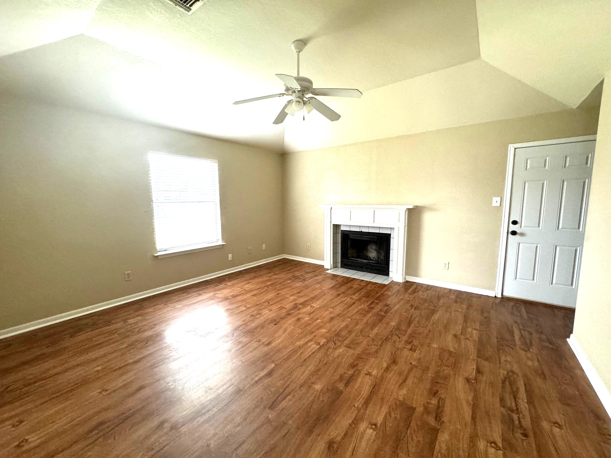 117 Quail Cove, Unit A Lockhart, TX 78644 - Photo 10 of 12 an empty room with wooden floor fireplace and windows