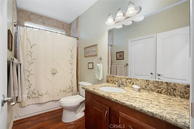 a bathroom with a granite countertop sink a toilet and a large mirror