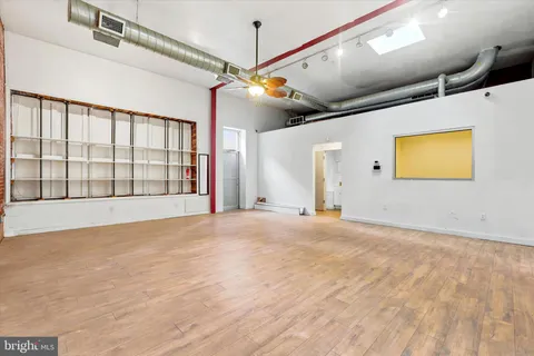 a view of an empty room with chandelier fan and a large window
