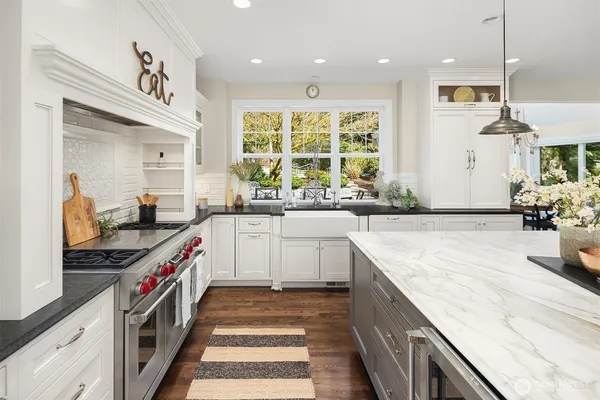 a kitchen with kitchen island granite countertop a sink a counter top space appliances and cabinets