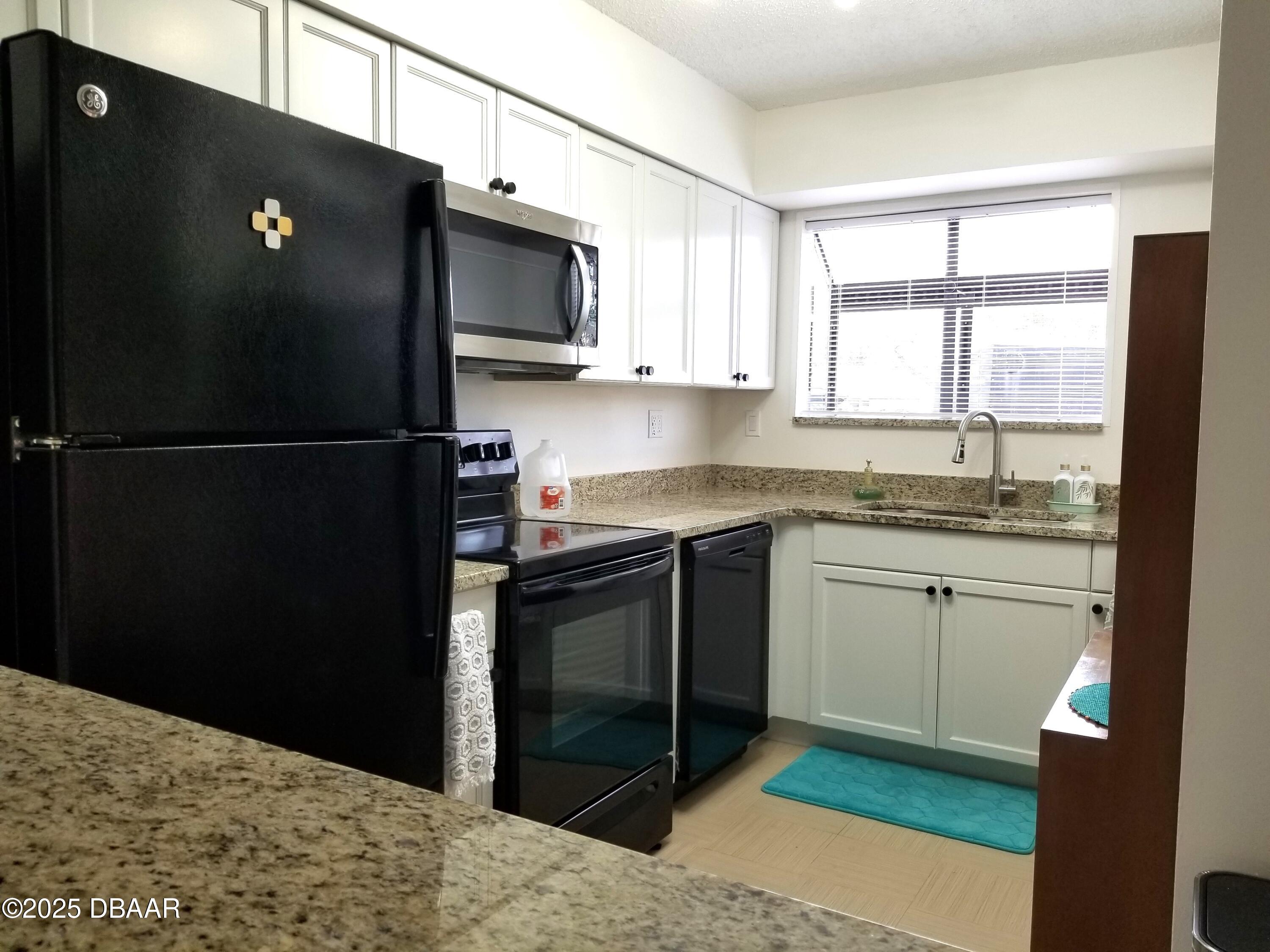 165 White Fawn Drive, Unit MB Daytona Beach, FL 32114 - Photo 5 of 34 a kitchen with a refrigerator and a sink