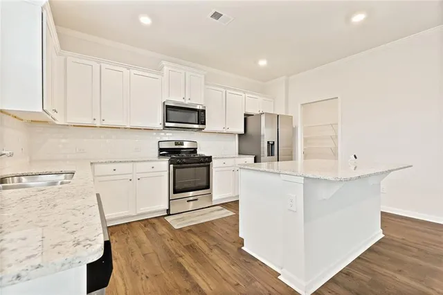 a kitchen with granite countertop white cabinets and stainless steel appliances