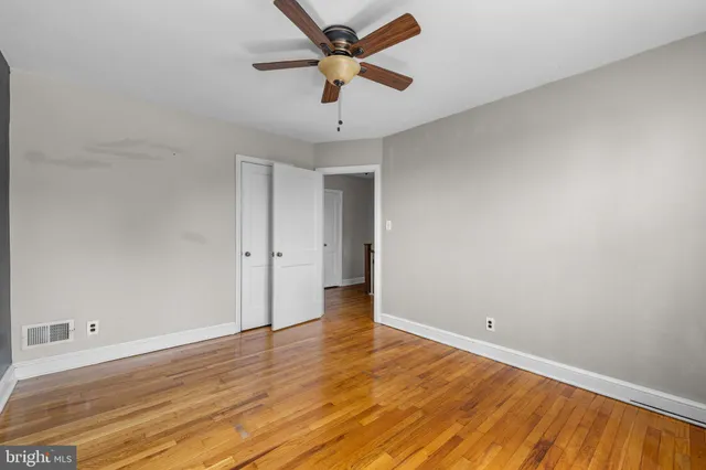 an empty room with wooden floor and a ceiling fan