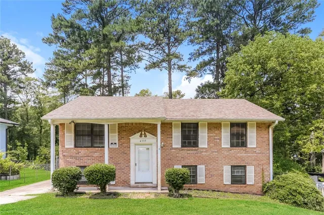 a front view of a house with a yard and trees