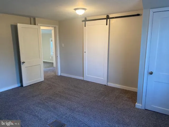 a view of an empty room with closet and wooden floor