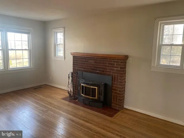 an empty room with wooden floor fireplace and windows