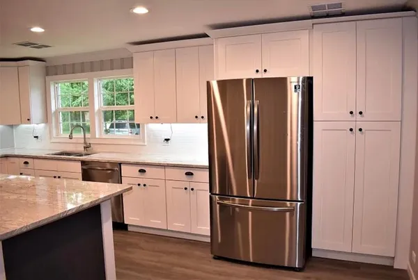 a kitchen with a refrigerator a sink cabinets and wooden floor
