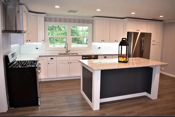 a kitchen with stainless steel appliances granite countertop a refrigerator a sink a stove and white cabinets with wooden floor