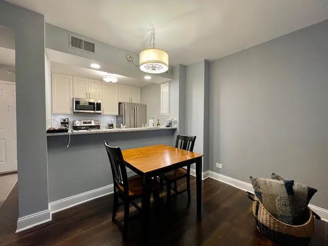 a kitchen with stainless steel appliances granite countertop a stove top oven a refrigerator a sink and a dining table with wooden floor