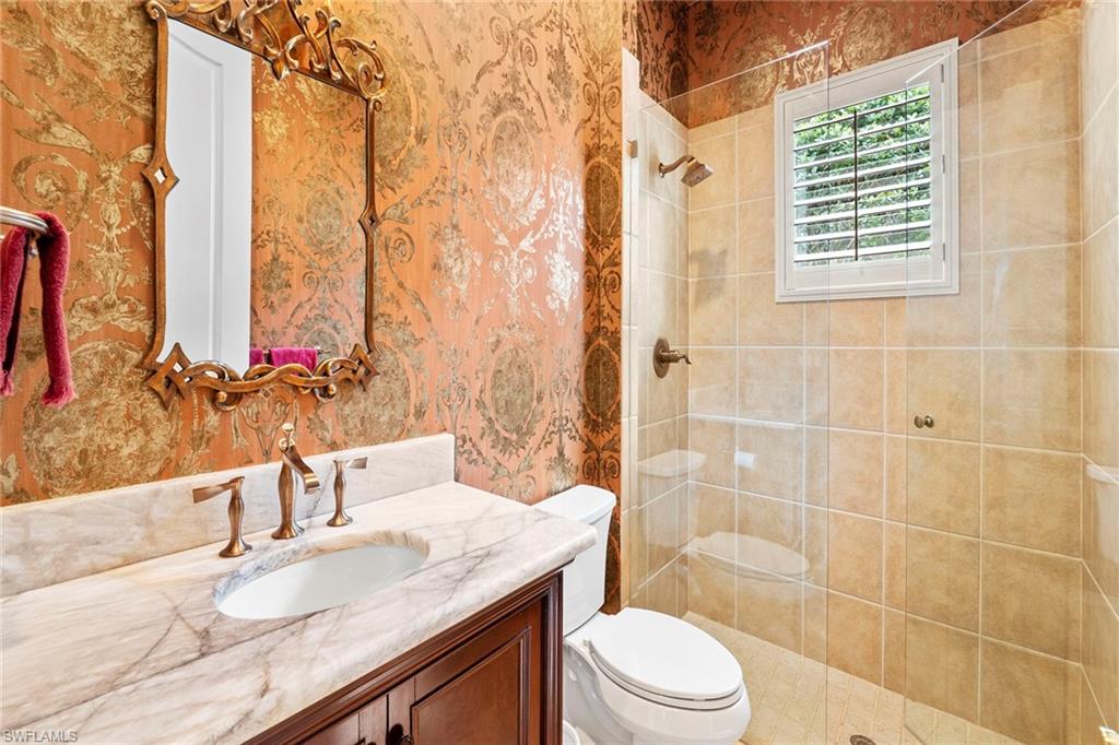 18071 Lagos Way Naples, FL 34110 - Photo 18 of 44 a bathroom with a granite countertop sink a toilet and shower