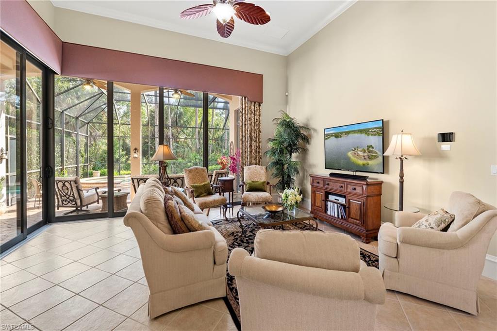 18071 Lagos Way Naples, FL 34110 - Photo 23 of 44 a living room with furniture a flat screen tv and a floor to ceiling window