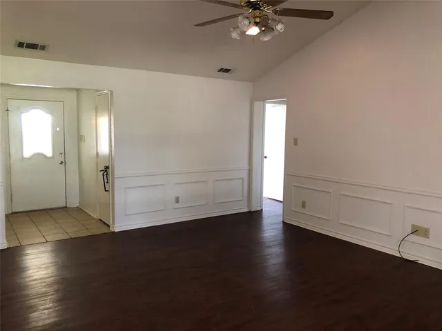 an empty room with wooden floor cabinet and windows