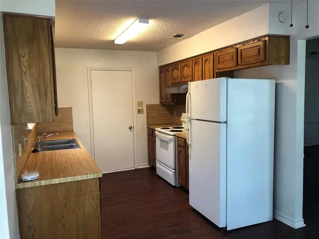 a white refrigerator freezer and a wooden floor