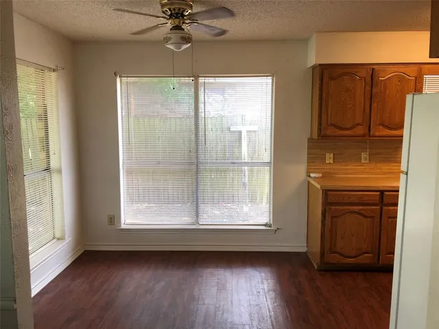 a view of a livingroom with wooden floor a ceiling fan and windows