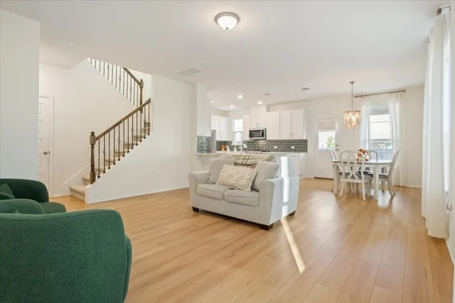 a living room with furniture and kitchen view with wooden floor