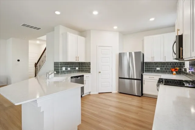 a kitchen with a refrigerator a stove top oven a sink and cabinets