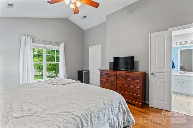 a room with wooden floor and a chandelier fan