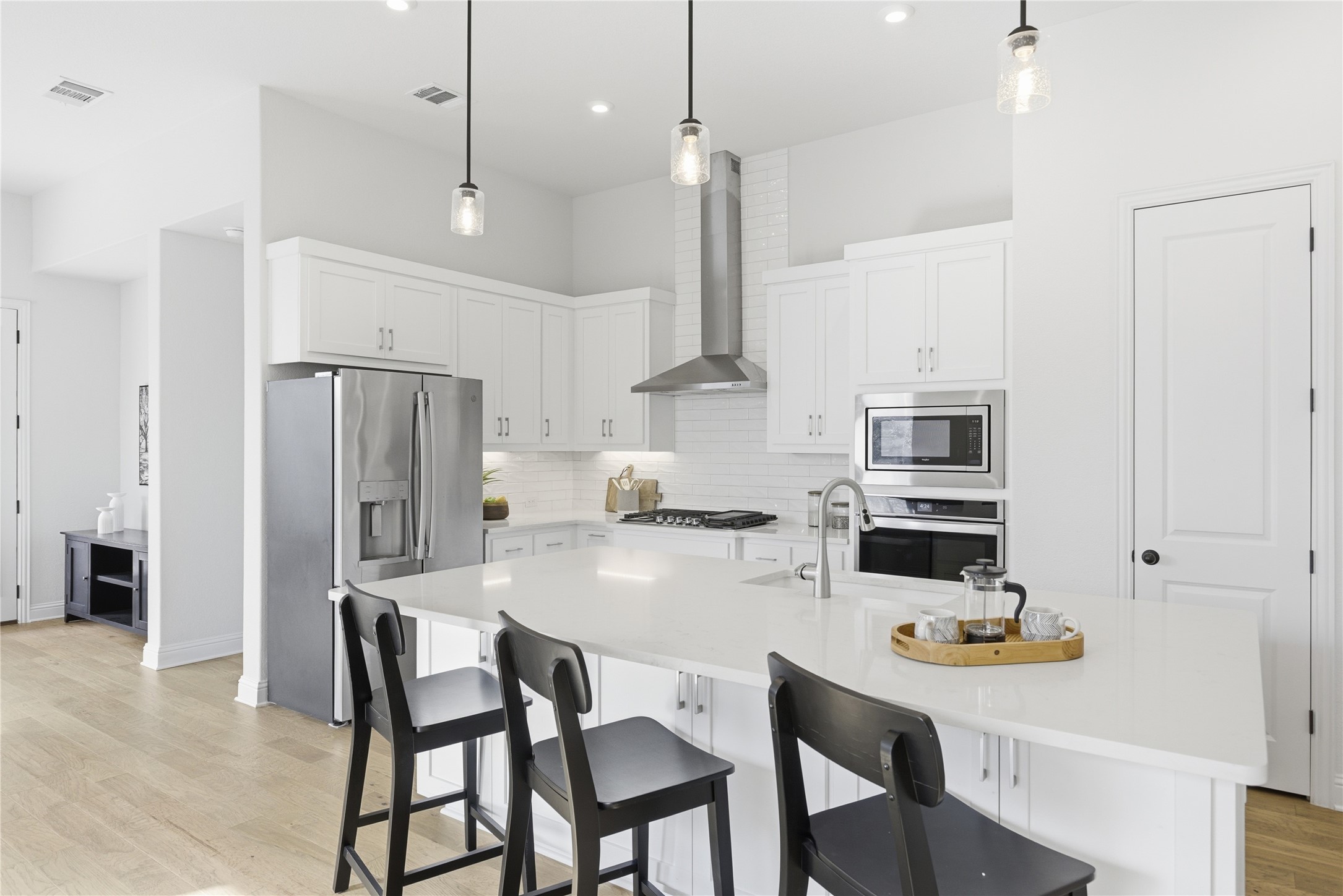225 Diamondback Drive Georgetown, TX 78628 - Photo 2 of 40 Kitchen with light wood-style flooring, stainless steel appliances, white cabinets, a breakfast bar with sink, and pendant lighting.
