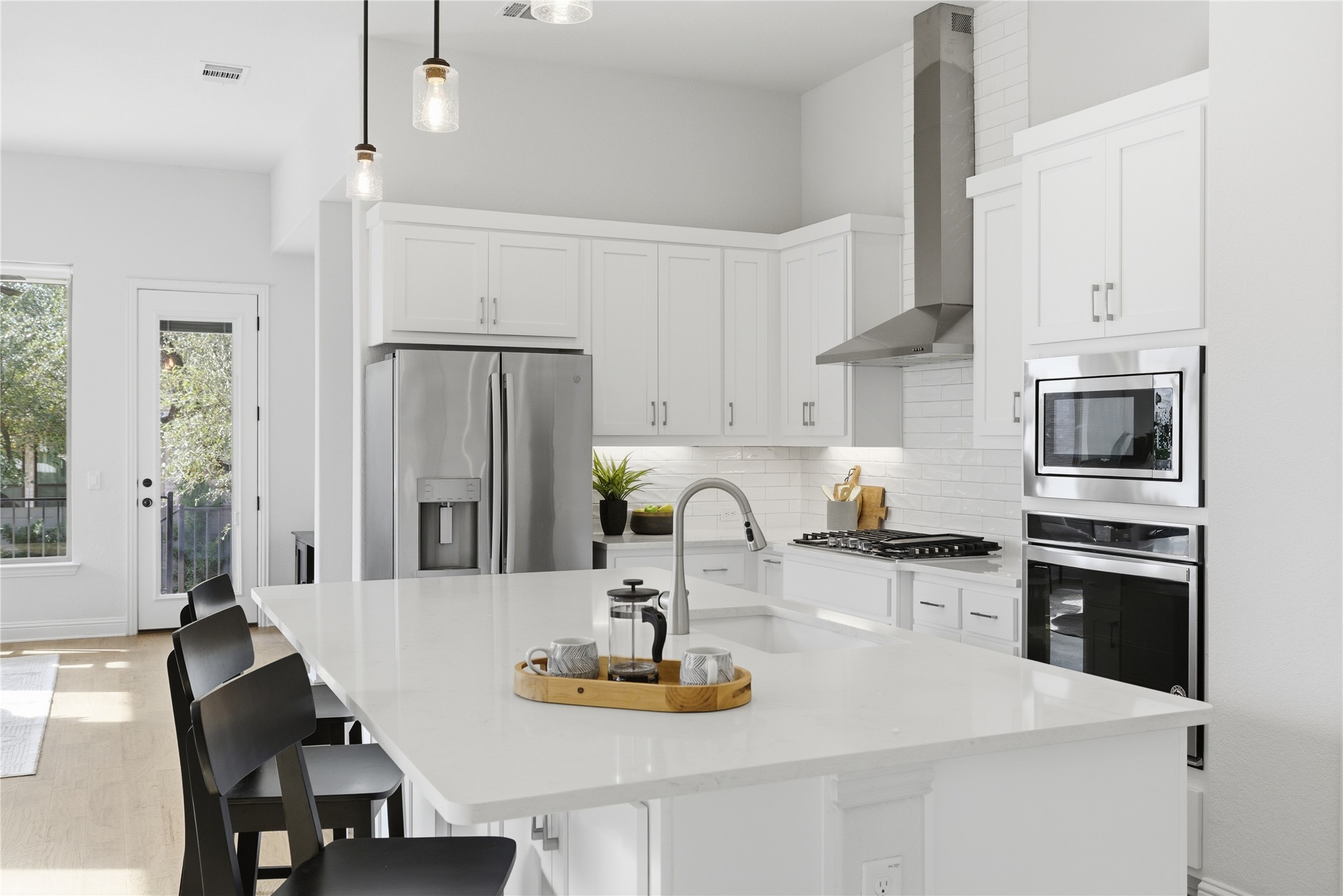 225 Diamondback Drive Georgetown, TX 78628 - Photo 5 of 39 Kitchen with light wood-style flooring, stainless steel appliances, white cabinets, a breakfast bar with sink, and pendant lighting.